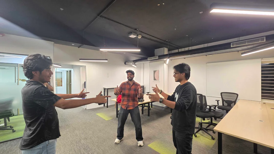 Three team members in the middle of the open office, gesturing and laughing together.