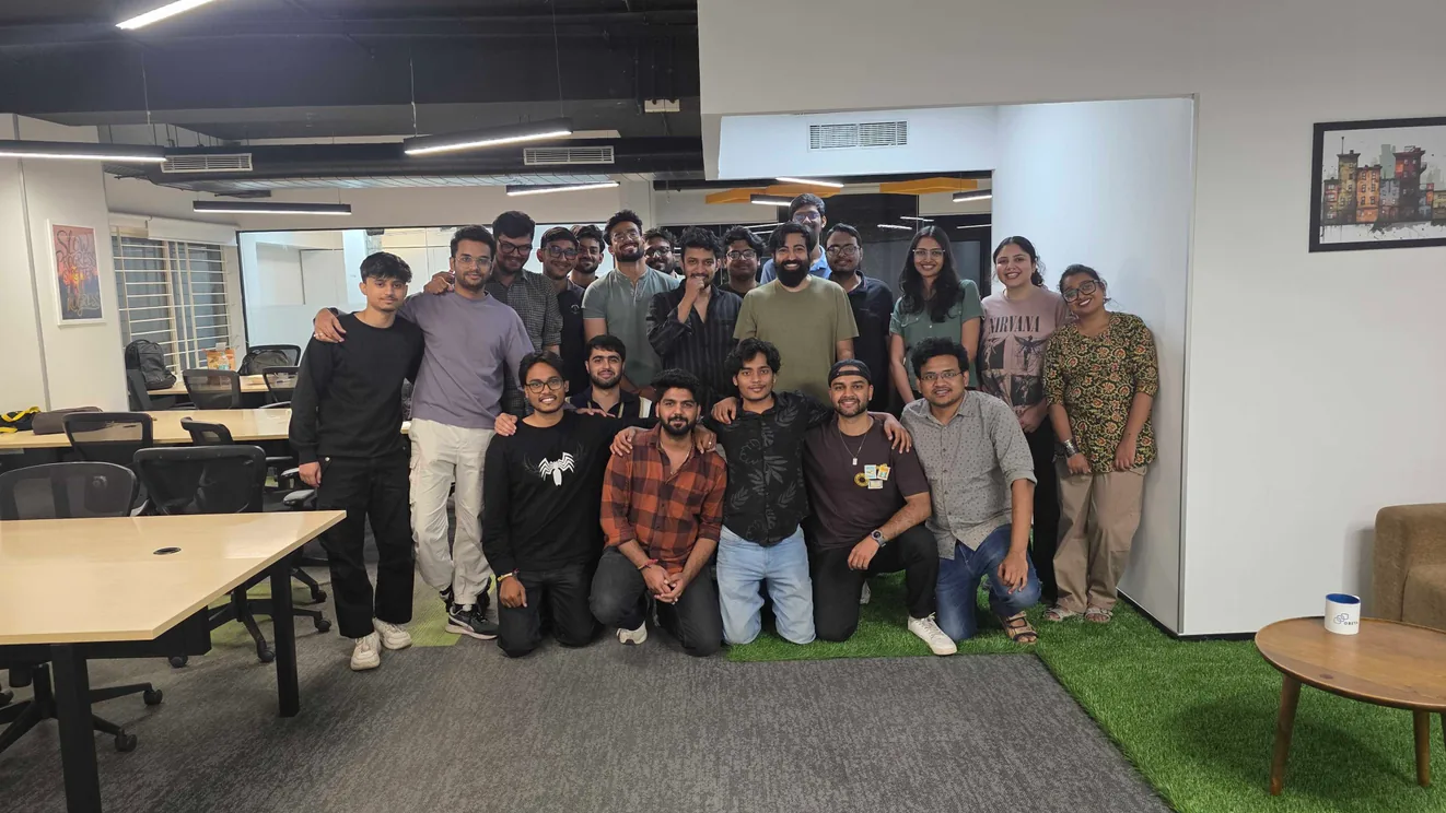 About thirty members of the Vel Labs team posed together in the office, some kneeling on a patch of artificial grass at the front.